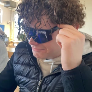 Svart quiltad jacka med dragkedja - Snygg svart quiltad jacka med dragkedja och huva. Perfekt för kyligare dagar med sin stilrena design och praktiska fickor. Jackan har en diskret logga på ärmen och en bekväm passform.