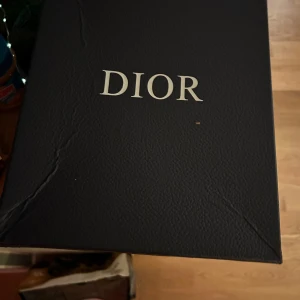 B22 dior - Sprillans nya.Snygga svarta sneakers från Dior med vita detaljer och snörning. Skorna har en modern design med märkets logga synlig på sidan. Perfekta för en stilren look. Storlek 42