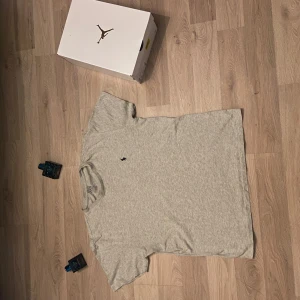 Grå t-shirt från Polo Ralph Lauren - Säljer en klassisk grå t-shirt från Polo Ralph Lauren i 100% bomull. T-shirten har en liten broderad logotyp på bröstet och är kortärmad. Perfekt för en stilren och avslappnad look. Helt ny använd fåtal gånger.