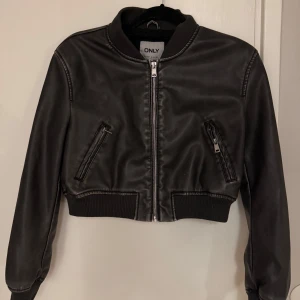 Svart bomberjacka från ONLY - Snygg svart bomberjacka från ONLY med dragkedja framtill och ribbade muddar. Jackan har två fickor med dragkedjor och en klassisk bomberkrage. 