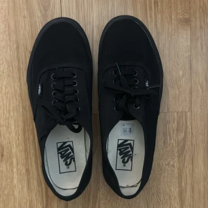 Svarta sneakers från Vans - Snygga svarta sneakers från Vans med klassisk design och snörning. Perfekta för en avslappnad stil. Gummisula och diskret logga på sidan. Ord pris 799 kr.