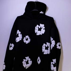 Denim Tears Hoodie - Helt ny Denim Tears Hoodie med vita mönster över hela plagget. Hoodien har långa ärmar och en bekväm huva. Perfekt för en avslappnad stil.