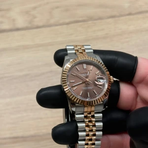 Seiko mod - Snygg seiko-klocka med en kombination av silver och guld på länken. Urtavlan är brun med tydliga markeringar och datumvisning. Perfekt för den som vill ha en elegant och tidlös stil.