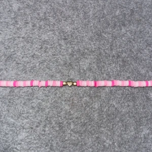 Rosa och vita armband med hjärtdetalj - Charmigt armband med rosa och vita pärlor och en söt hjärtdetalj i guld. Perfekt för att lägga till en färgglad touch till din stil.