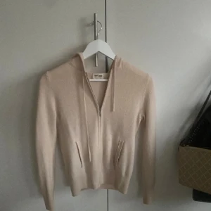 Beige hoodie från Soft Goat - Mysig beige hoodie från Soft Goat med dragkedja och huva. Tröjan har långa ärmar och ribbade muddar vid ärmslut och nederkant. Perfekt för kyliga dagar.