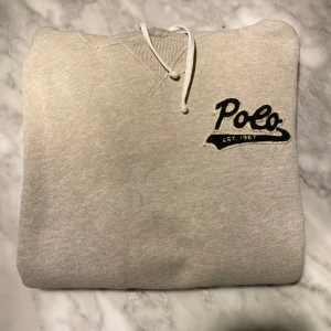 Grå Ralph Lauren hoodie  - Skick: 7,5/10. Tröjan har en liten fläck samt har en sömn brustit lätt, fråga bara om bild så skickar jag! Om du är osäker på om den kommer passa kan du alltid fråga om mått!