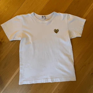 Vit t-shirt från Comme des Garçons - Vit t-shirt Play från Comme des Garçons, CTG.  Hel och ren, inga hål eller fläckar. Barnstorlek M, skulle säga att den är ungefär som 140-150 cl.