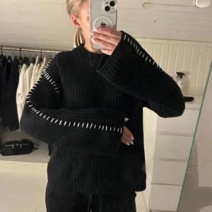  Svart stickad tröja med vita detaljer - svart stickad tröja med unika vita sömdetaljer längs ärmarna. Tröjan har en avslappnad passform och långa ärmar, perfekt för kyligare dagar. Den är både stilren och bekväm. Storlek xs men passar även s och aldrig använd!💌