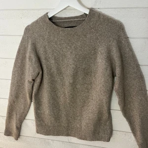 Beige stickad tröja - Mysig beige stickad tröja med rund hals och långa ärmar. Perfekt för kyliga dagar med ribbstickade muddar vid ärmslut och nederkant. Använd ett par gånger. 