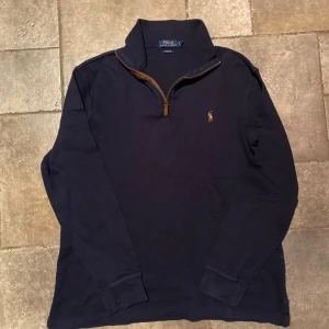 Ralph Lauren Half Zip Large  - Säljer en stilren mörkblå Half/Quarter zip från Polo Ralph Lauren med dragkedja och broderad logotyp på bröstet. Perfekt för en avslappnad men ändå snygg look. Tröjan är i storlek Large och i väldigt fint skick.