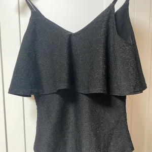 Glittrig body - Sjuukt snygg body från gina tricot! Säljer då den tyvärr inte kommer till användning😔Svart och glittrig, passar till t.ex fest men mycket annat också! Pris kan alltid diskuteras😊Kontakta mig för fler bilder eller om du har en liten eller stor fråga!❤️