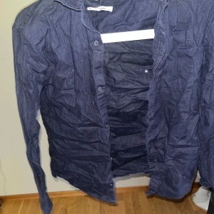 Mörkblå skjorta - Snygg mörkblå skjorta med knappar framtill. Perfekt för en stilren look. Skjortan har långa ärmar och är tillverkad i ett linne och bomulls material. Köpt från Cubus. 