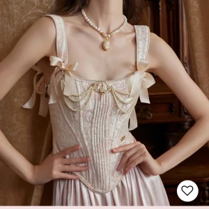 Lacemade Rosa korsett med kjol - Elegant rosa korsettklänning i satin med vackra pärldetaljer och rosetter. Klänningen har en volangkjol och justerbara axelband. Perfekt för en speciell tillställning. Aldrig använd . Köpt från Lacemade för 89€ (korsett) 64€ (kjol) Kontakta gärna för mer frågor Priset kan diskuteras med inte mindre än 1000kr då jag köpte setet för 1700kr