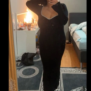 Svart långklänning från Gina Tricot - Stickad tjock klänning från Ginatricot med figurnära passform. Köptes för original priset 499 men vill helst ha den billigare då den är använd 3 gånger. Med hjärtformad ringning med vit söm. Den har lång ärm, Storlek M men den är väldigt stretchig så L passar också, är 160 så den är lång på mig❤️