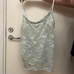 Mintgrön spetslinne - Säljer ett mintgrönt linne med vacker spetsdetalj. Linnet har tunna justerbara axelband och ett blommigt mönster i spetsen. Perfekt för en somrig söt look. På axelbanden så är det små söta rosetter💞Hittade ej någon lapp!