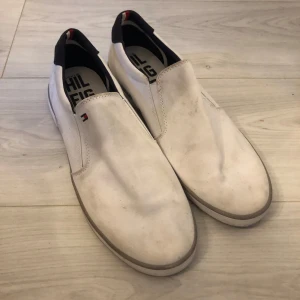 Vita loafers från Tommy Hilfiger - Snygga vita loafers från Tommy Hilfiger med en stilren design. Skorna har en diskret logga på ovansidan och är perfekta för en avslappnad look.