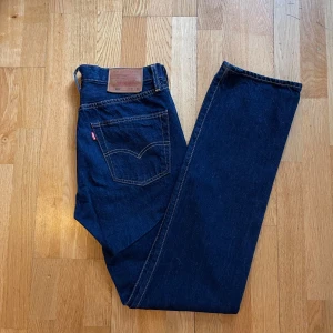 Levis 501 jeans i mörkblå denim nyskick - Klassiska Levis 501 jeans i mörkblå denim. Dessa jeans har en rak passform och är tillverkade i slitstarkt denimtyg. Dem är bara använda en eller två gånger. Är i ett nyskick. Storlek W31 L34