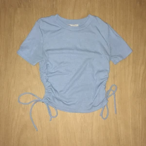 Ljusblå ribbad topp från Zara - Säljer en ljusblå ribbad topp från Zara med korta ärmar och knytning i sidorna. Perfekt för sommaren!  Mycket mjuk och bekväm, inga defekter och i jättebra skick!☀️🌊⛱