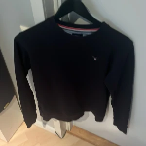 Mörkblå tröja från GANT - Säljer en stilren mörkblå  tröja från GANT med deras klassiska logga på bröstet. Tröjan har långa ärmar och en rund halsringning. Perfekt för en avslappnad och snygg look. Pris kan diskuteras vid en snabb affär !