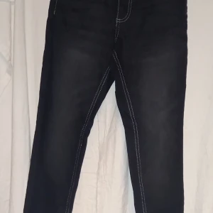 Svarta stretchjeans från Pepperts - Snygga svarta stretchjeans från Pepperts i storlek 146. De har kontrasterande vita sömmar och klassisk femficksdesign. Perfekta för en stilren look.