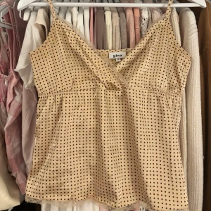 Vintage Beige prickig linnetopp  - Säljer en söt beige babydoll linnetopp från Gina (INTE GinaTricot )med bruna prickar och spetsdetaljer. Toppen har smala axelband som är justerbara och en omlott-design framtill. 