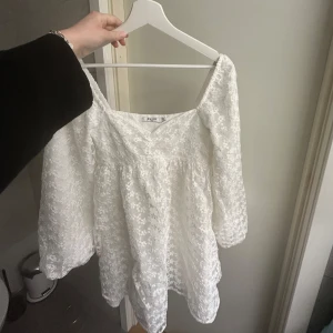 Vit spets klänning från nakd - Charmig vit klänning i spets från nakd med offshoulder-design. Perfekt för en romantisk look med sina långa ärmar och vackra spetsdetaljer. Perfekt för studenten!