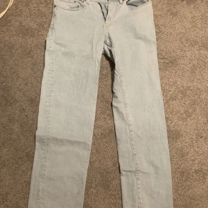Ljusblå jeans - Säljer ett par ljusblå jeans med klassisk femficksdesign från H&M. Byxorna är i regular fit och är perfekta för en avslappnad stil. De har en dragkedja och knapp framtill.        Storlek: 29/32