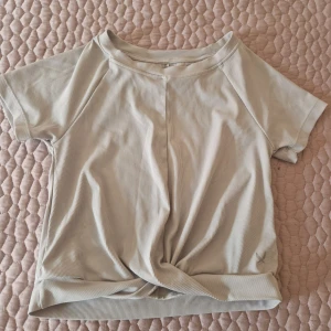 Beige ribbad topp - Säljer en stilren beige ribbad topp med korta ärmar. Perfekt för en avslappnad look. Toppen har en enkel design med rund hals och mjukt material.