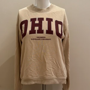 En tunn sweatshirts med tryck - En tunn, beige sweatshirt med tryck på framsidan. Bra skick 