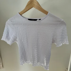Vit ribbad topp - Säljer en snygg vit ribbad topp. Den är kortärmad och har en enkel, stilren design. Toppen är i nyskick.🤍