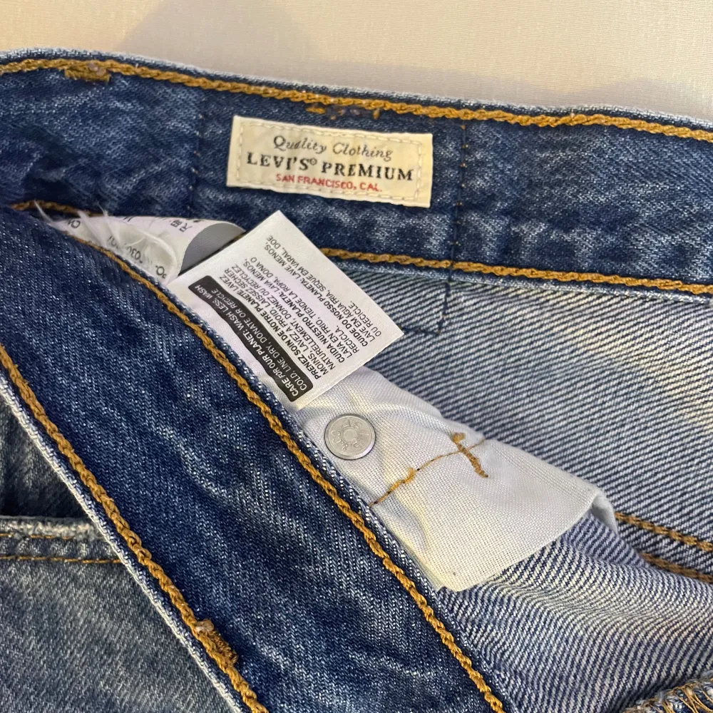 Säljer ett par snygga blå jeansshorts från Levi's. De är i storlek W26 och har en klassisk femficksdesign med knappar framtill. Shortsen har en uppvikt kant och är i nyskick. Perfekta för sommaren!. Shorts.