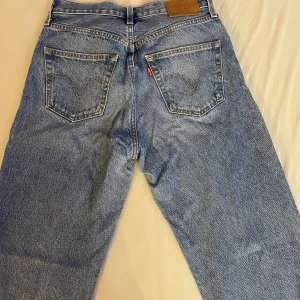 Levis 501 jeans i blått - Säljer ett par klassiska Levis 501 jeans i blått. De är i storlek W25 L32 och har en knappgylf. Jeansen är i bra skick och har den ikoniska Levis-lappen på baksidan. Perfekta för en casual look!