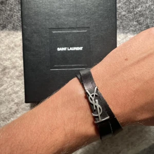 Saint Laurent armband  - Dubbelvikt YSL armband i svart. Passar både killar och tjejer. Skicket är väldigt bra utan några tydliga defekter. Nypris ≈ 3.500kr. Skriv privat vid frågor/funderingar.