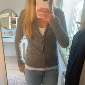 Grå zip up - Grå stickad zip up tröja från Pull & bear. Använd fåtal gånger och i bra skick. Storlek M men sitter som XS. Den har tumm hål i armarna men man kan vika upp de om man ej vill ha det💞