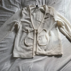 Vit ribbad kofta - Säljer en superfin vit ribbad kofta i storlek S. Den har långa ärmar och knytband framtill. Perfekt för både vår och höst! Koftan är i nyskick och väldigt bekväm att ha på sig. Passar till både vardag och fest. 🌸