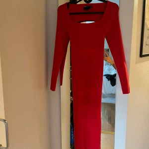 Röd långklänning med öppen rygg - Säljer en superfin röd långklänning med långärmad design. Klänningen har en snygg öppen rygg och är tight passform. Perfekt för fest eller bal! Materialet känns som bomull och den är i nyskick. Passar perfekt till höst och vinter.