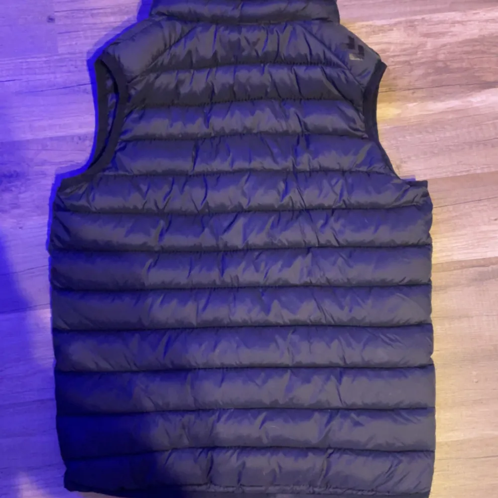 Säljer en svart dunväst i storlek 150. Västen är perfekt för höst och vinter, med en dragkedja framtill och två fickor på sidorna. Den är i nyskick och har en normal passform. Västen är både stilren och praktiskt. Sänker priset vid snabb affär . Takit.