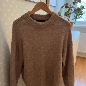 Beige stickad tröja  - Mysig beige stickad tröja från Lager157 i storlek XS. Perfekt för kyliga dagar med sin klassiska design och ribbade detaljer vid hals och ärmslut. En tidlös favorit i garderoben! Köpt för 200kr!