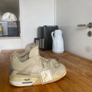 Beige Nike sneakers med snörning - Snygga beige Nike sneakers med snörning och texten 'AIR' på sulan. Skorna har en stilren design med meshdetaljer och en robust sula. Perfekta för en avslappnad stil.