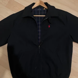 Svart jacka från Polo Ralph Lauren - Snygg svart jacka från Polo Ralph Lauren med röd broderad logga på bröstet. Har endast använt ett gång då den är stor på mig. 