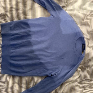 Blå tröja från Polo Ralph Lauren - Säljer en stilren blå tröja från Polo Ralph Lauren. Tröjan har en klassisk design med rund hals och långa ärmar. Perfekt för en avslappnad och elegant look. Size S.