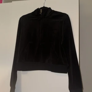 Svart velour hoodie från Juicy Couture - Säljer en svart velour hoodie från Juicy Couture med dragkedja och broderad logga på bröstet. Tröjan har långa ärmar och en mysig känsla, perfekt för en avslappnad stil. Koftan är helt felfri utan fläckar och finns i ett djur/rökfritt hem