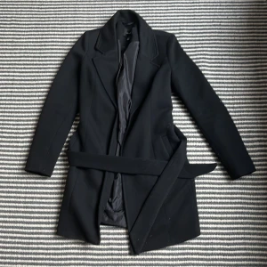 SVART KAPPA - Välanvänd svart kappa! Inga fläckar eller liknande! Har kollat igenom jackan och kan inte hitta några hål! Syns inte att den varit välanvänd!