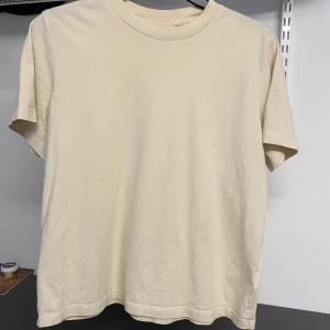 Beige t-shirt från & Other Stories - Säljer en beige t-shirt från & Other Stories. Den är tillverkad i mjuk bomull och har en klassisk rund halsringning. Perfekt basplagg för alla tillfällen.