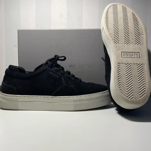 Svarta sneakers från Axel Arigato - Snygga svarta sneakers från Axel Arigato i mocka med vit sula. Skorna har klassisk snörning och en stilren design som passar perfekt till vardags. Perfekta för dig som gillar en minimalistisk stil.