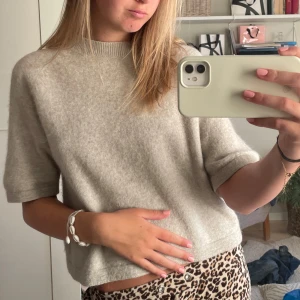 Beige stickad tröja - Säljer en mysig beige stickad tröja med korta ärmar. Perfekt för en avslappnad stil. Tröjan har en rund hals och är croppad för en modern look.