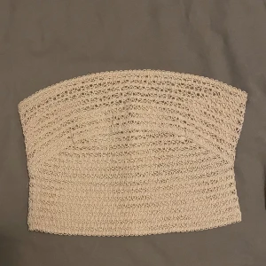 Beige bandeau top med dragkedja - Axelbandslös top från Bik Bok med mönster gjort av tjocka trådar och dragkedja på baksidan.