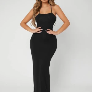 Svart långklänning med öppen rygg - Elegant svart långklänning med smala axelband och en stilren design. Klänningen har en öppen rygg med korsade band och knytning, vilket ger en sofistikerad look. Endast använd 1 gång 💗
