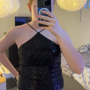 Svart glittrig topp från nakd - Snygg svart topp med glittriga paljetter och smala axelband. Perfekt för en festlig kväll. Toppen har en åtsittande passform och ger en elegant look. Använd 1 gång