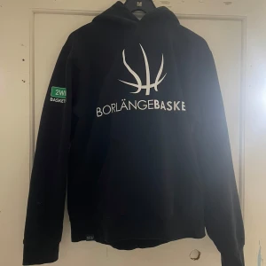 Svart hoodie från Southwest - Säljer en svart hoodie från Southwest med texten 'Borlänge Basket' och en basketbollgrafik på framsidan. På baksidan står det 'Göing'. Hoodien har långa ärmar och en klassisk huva. Perfekt för basketentusiaster!